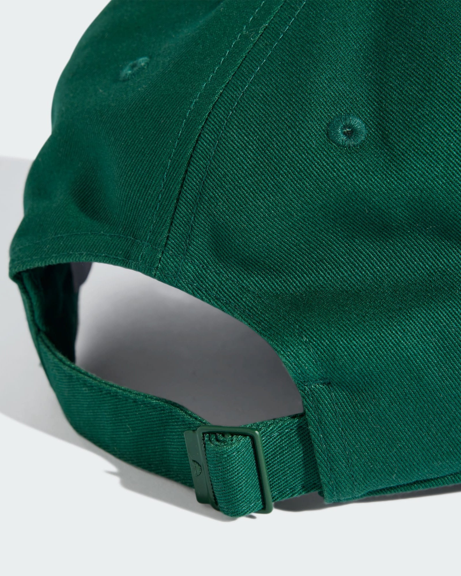 Close-up of the back of a green Adidas cap, featuring an adjustable fabric strap with a metal buckle and stitched eyelets.