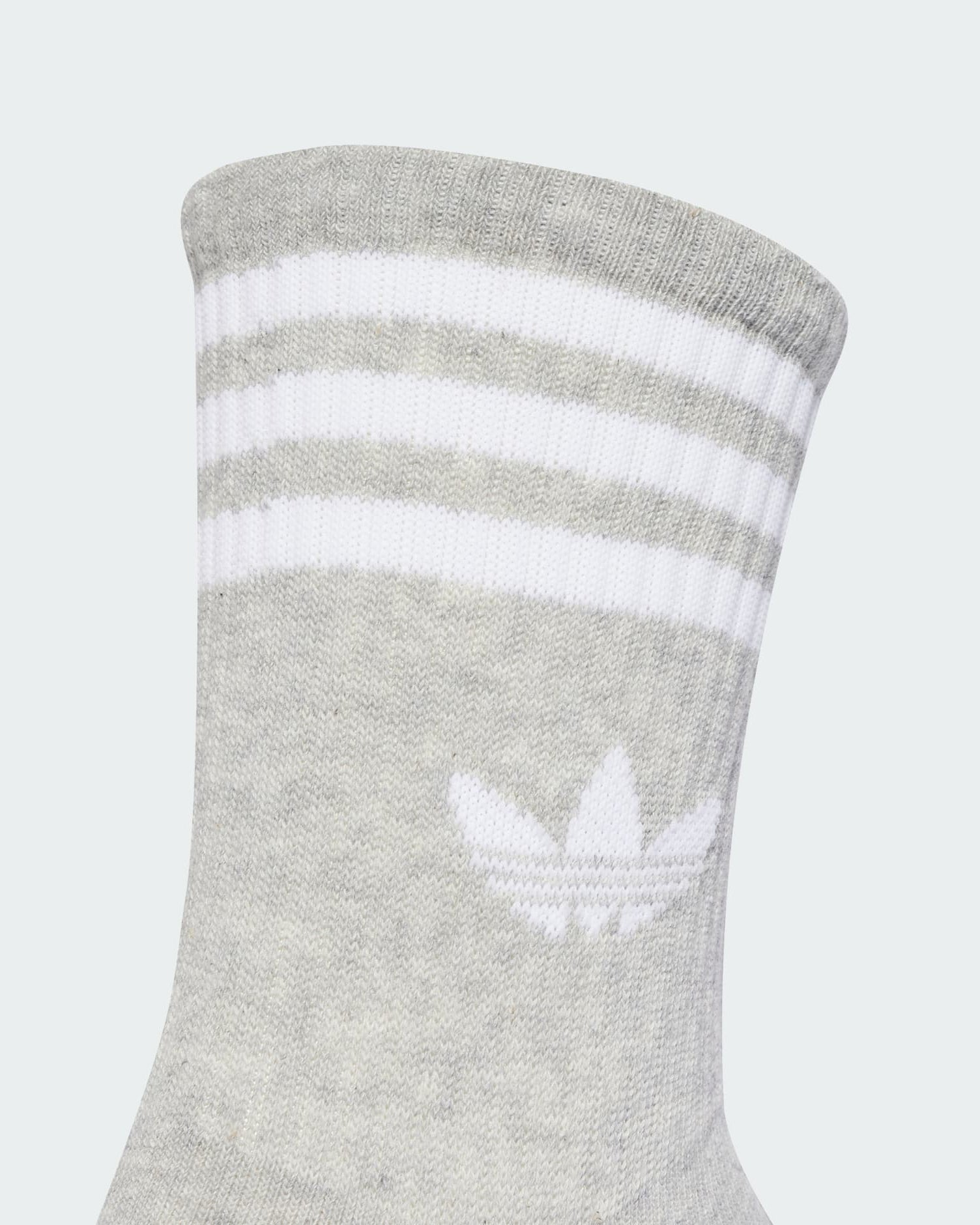 Close-up of grey Adidas sock featuring white Trefoil logo and triple stripe design.