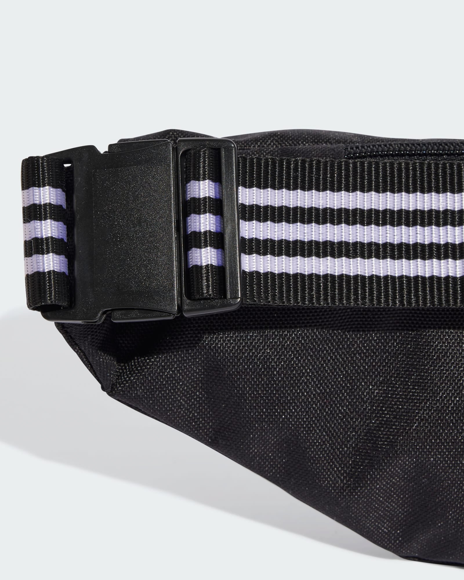 Adjustable strap with black and white stripes and buckle on adidas waist bag.