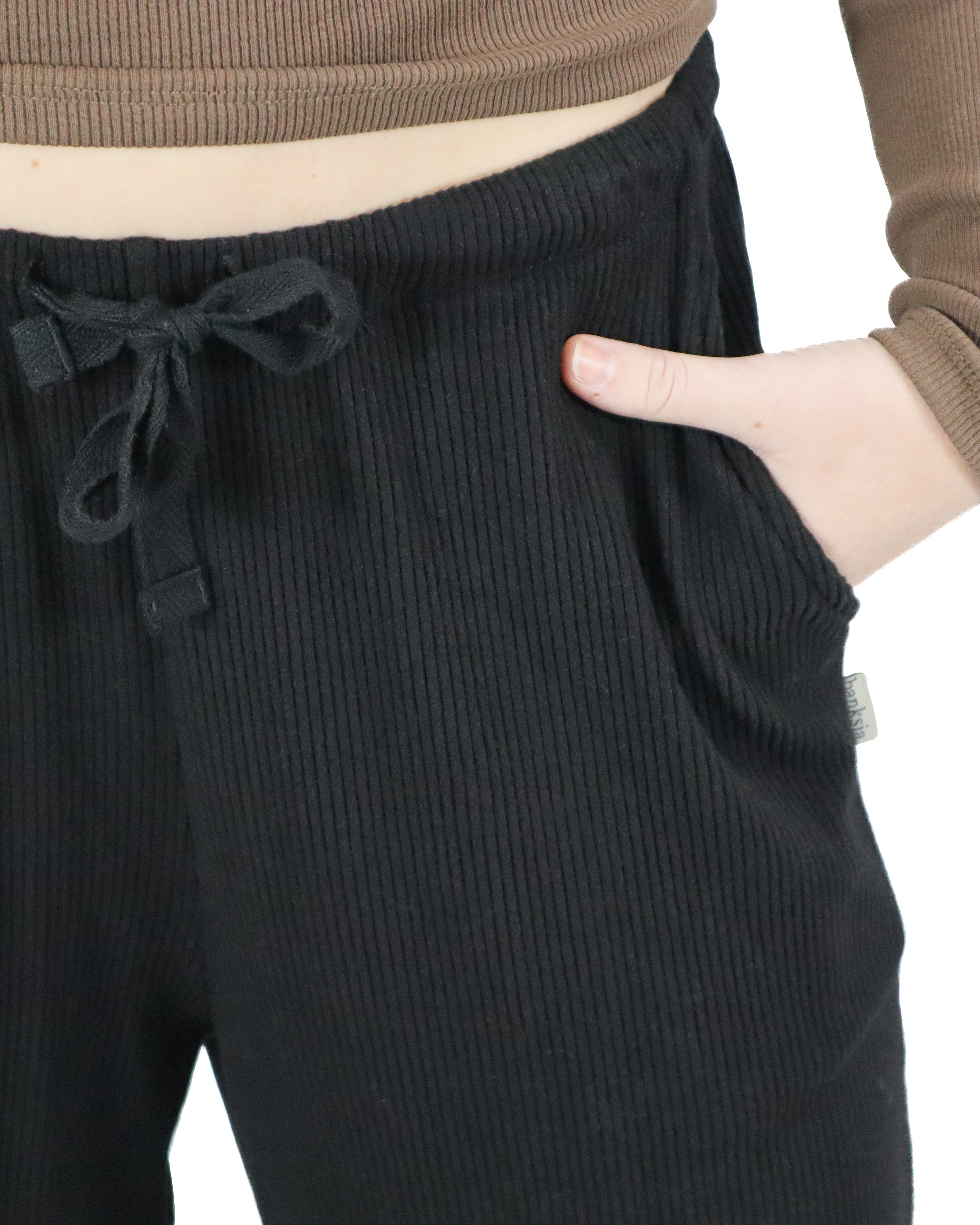 Close-up of black ribbed fabric pants with adjustable drawstring and side pockets
