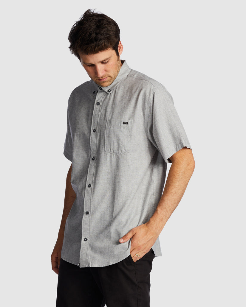 Rear angle of grey short sleeve shirt with curved hem and relaxed fit.