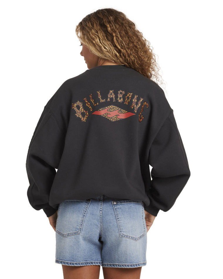 Back view of black Billabong crewneck with graphic logo across shoulders, paired with light denim shorts