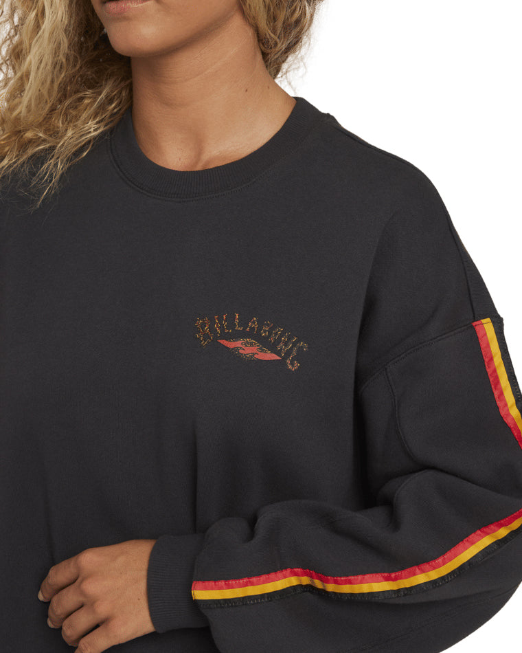 Close-up of black Billabong crewneck showing logo on chest and striped sleeve detail