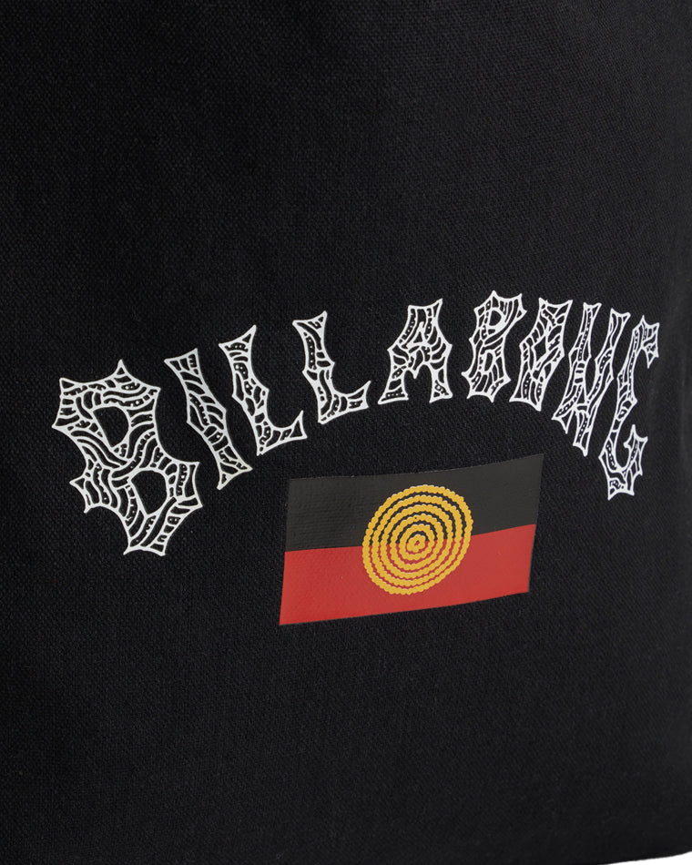 Close-up of white spiderweb-style Billabong logo and circular yellow and red artwork on black fabric