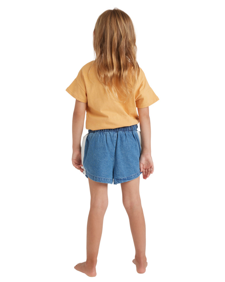 Back view of a girl wearing a yellow t-shirt and blue denim shorts with an elastic waistband.