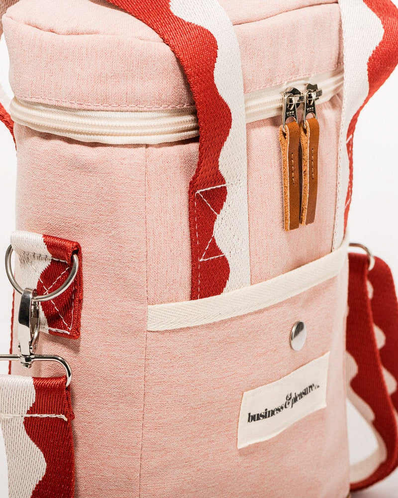 Close-up of pink wine cooler tote bag with leather zipper pulls, front pocket, and red wave-patterned strap detail.