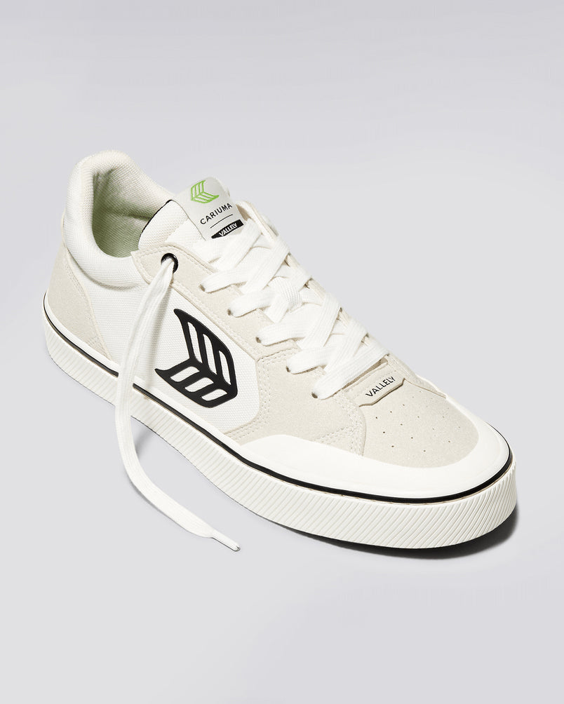 White Cariuma Valley sneaker with black leaf logo, lace-up closure, perforated toe box, and textured rubber sole.