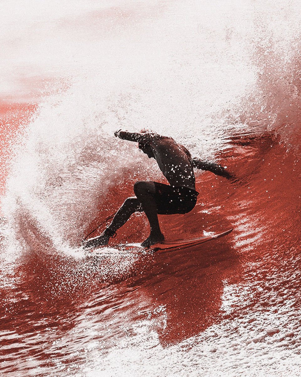 Surfer carving inside a wave with strong spray, showcasing style and control on a powerful turn.