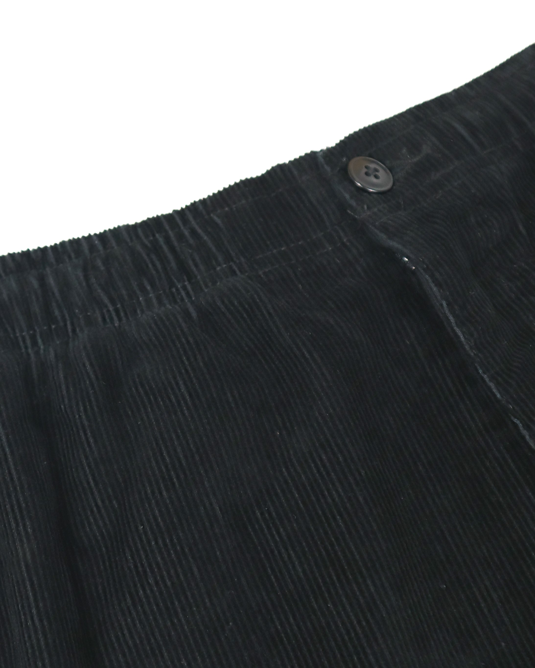 Close-up of black corduroy fabric with elastic waistband and button closure