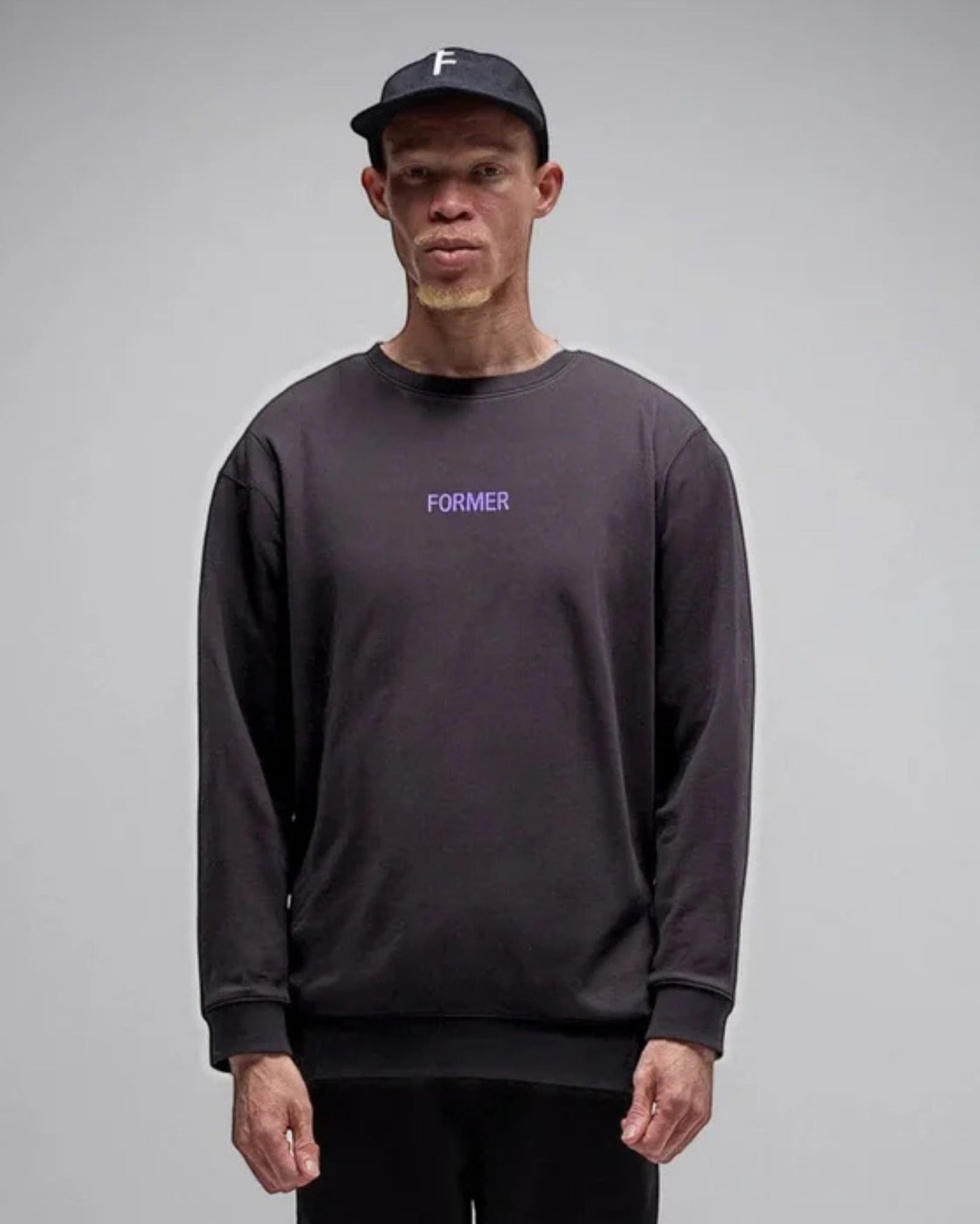Person wearing a dark long-sleeve shirt with 'FORMER' text on a gray background