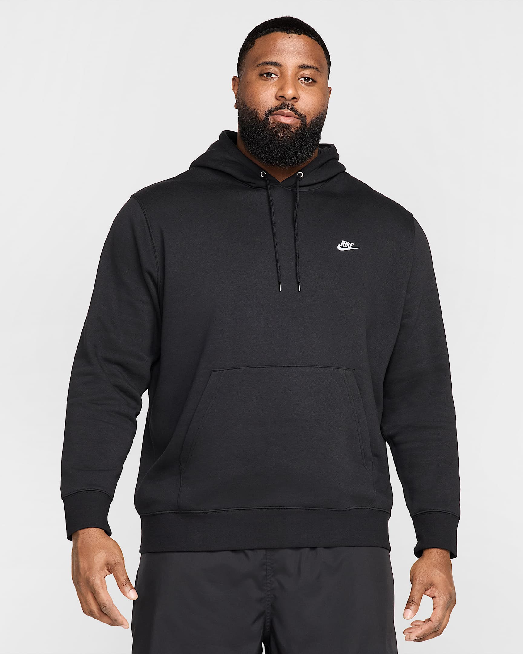 Plus-size man wearing a black Nike hoodie and black pants, front view.