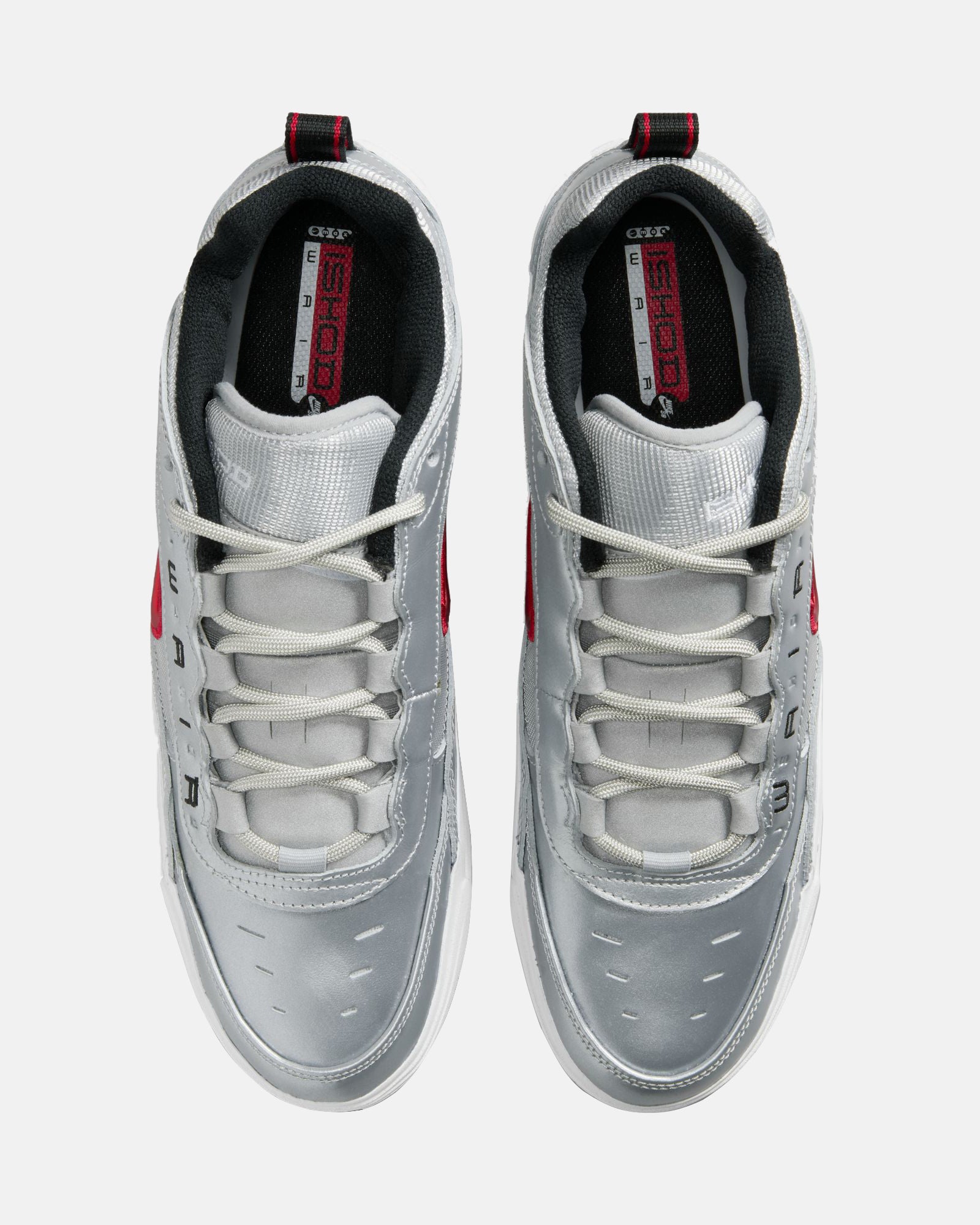 Top view of silver Nike Air Max sneakers featuring white laces, red branding on insoles, and black inner lining with red pull tabs.