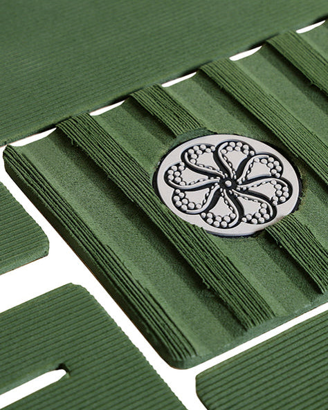 Close-up of green pad with raised central arch and circular textured logo detail.