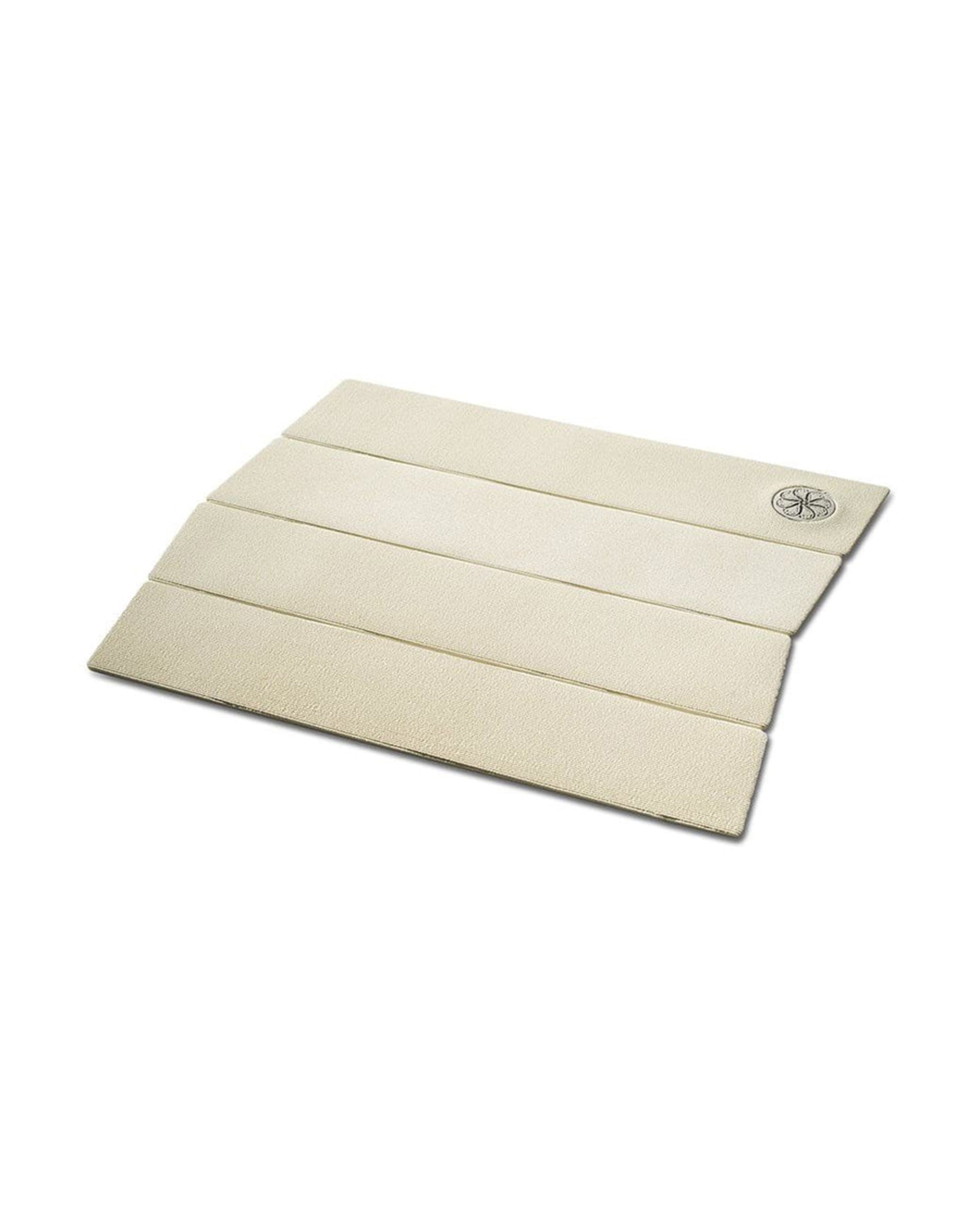 Angled view of white four-piece traction pad with ribbed grip texture and embossed logo.