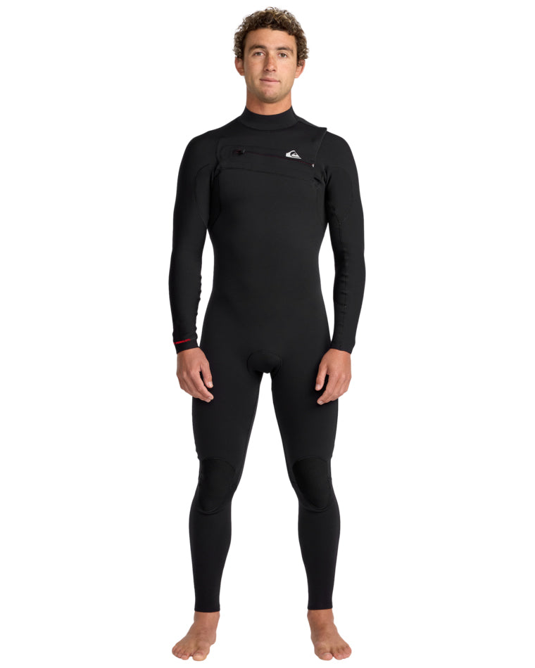 Man wearing a black full-length Quiksilver wetsuit with front chest zip, standing facing forward.