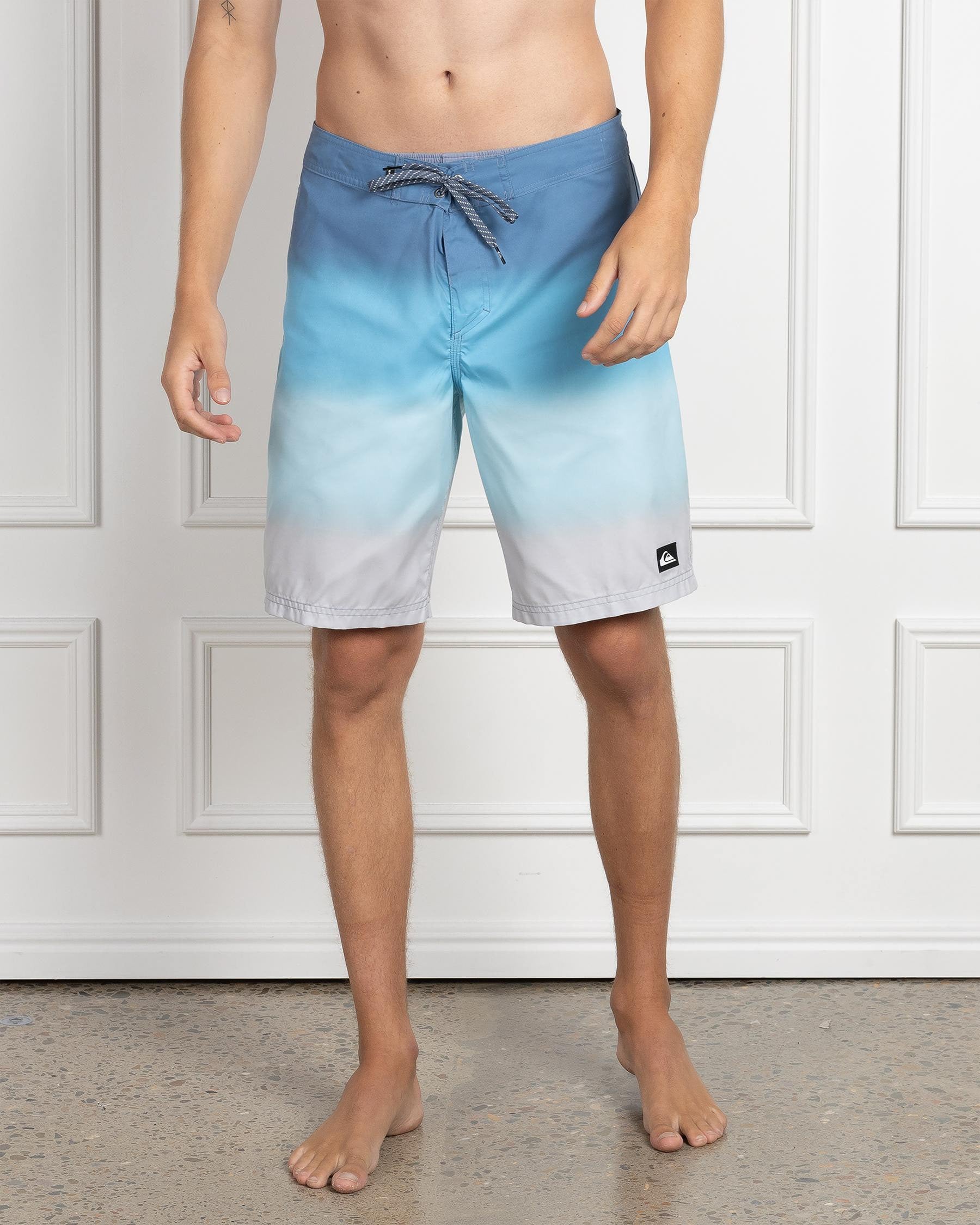Front view of blue to grey ombre Quiksilver boardshorts with drawstring waist and logo patch.