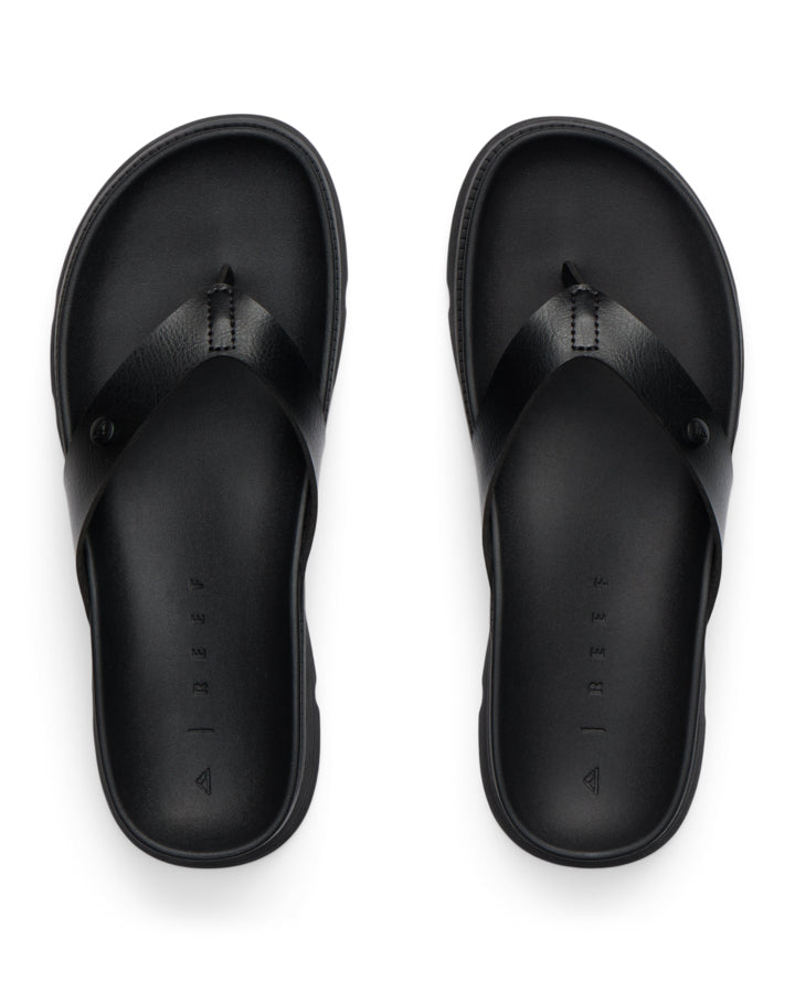 Top-down view of black sandals with leather-look straps and Reef branding