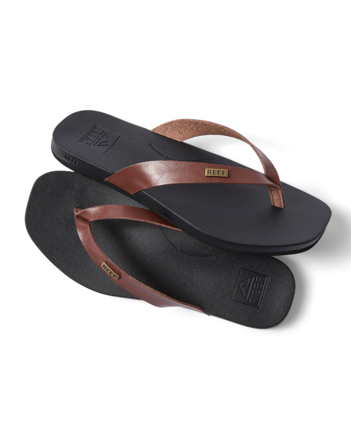 Flat lay of Reef thongs with black sole and brown vegan leather straps