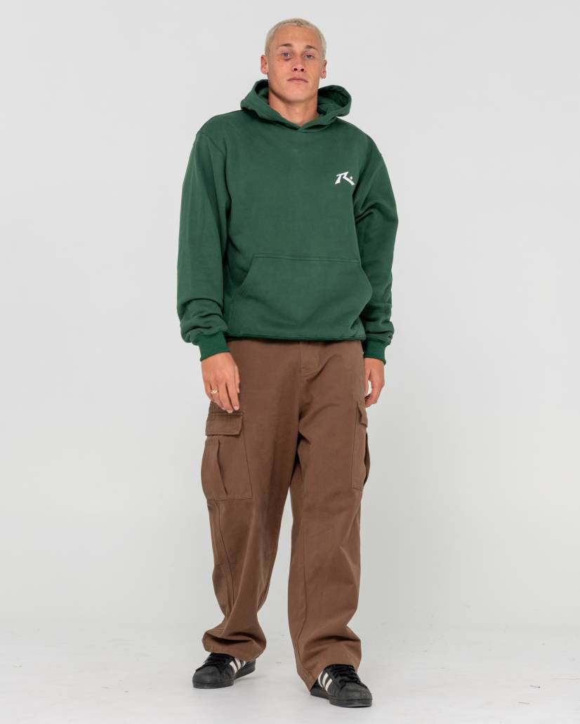 Full-body view of a model wearing a forest green hoodie with a white logo, brown cargo pants, and black sneakers.