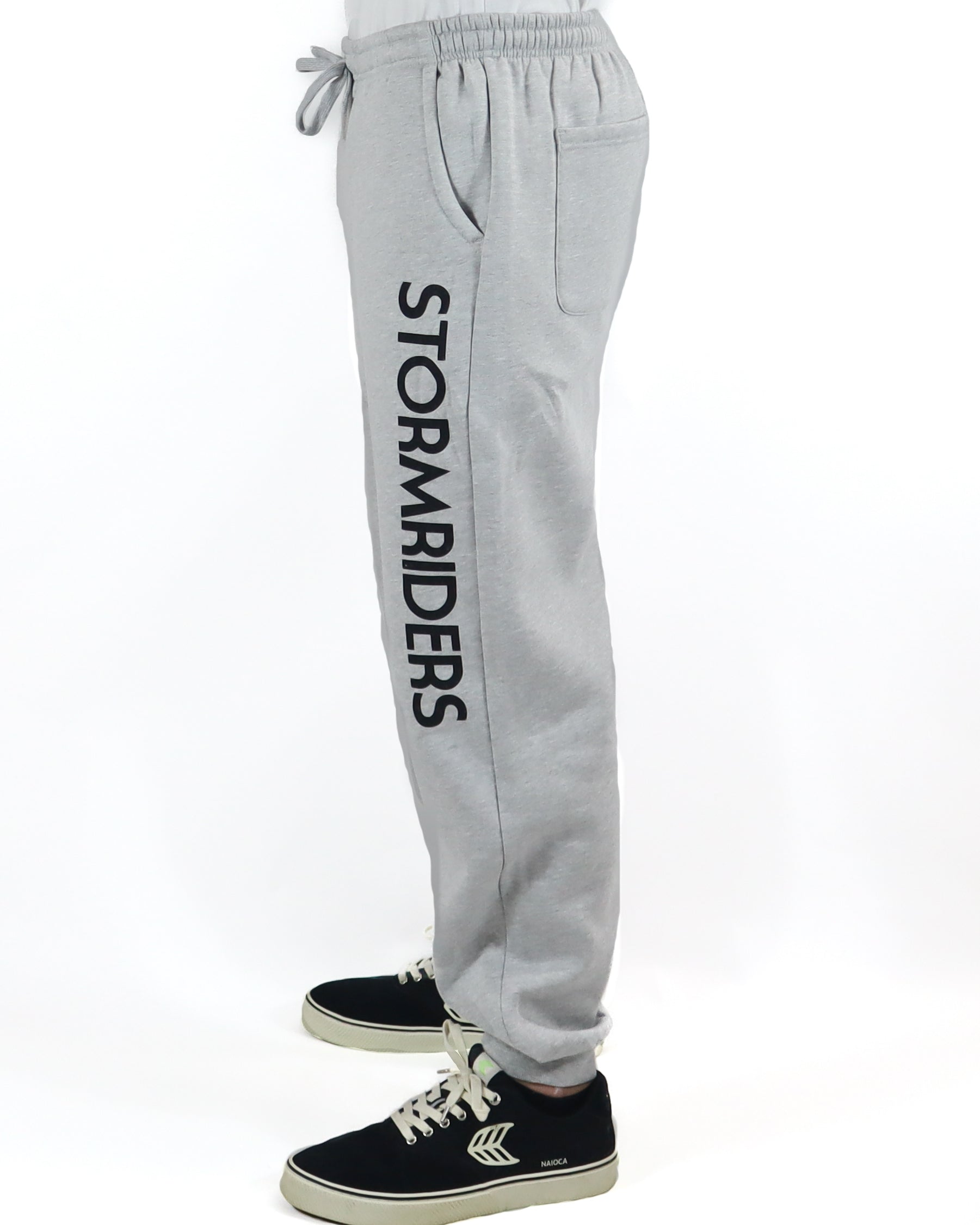 Side view of light grey Stormriders track pants with bold black logo.