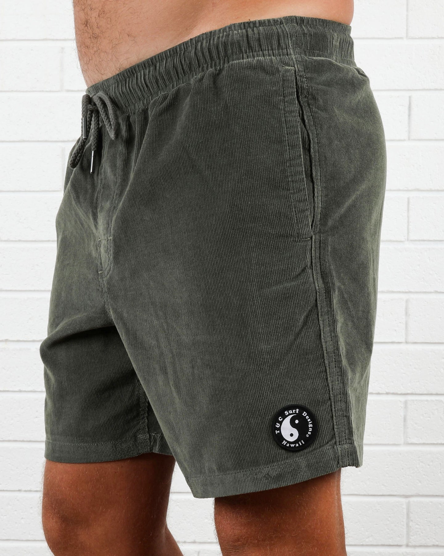Close up of olive cord shorts with elastic waistband and logo detail