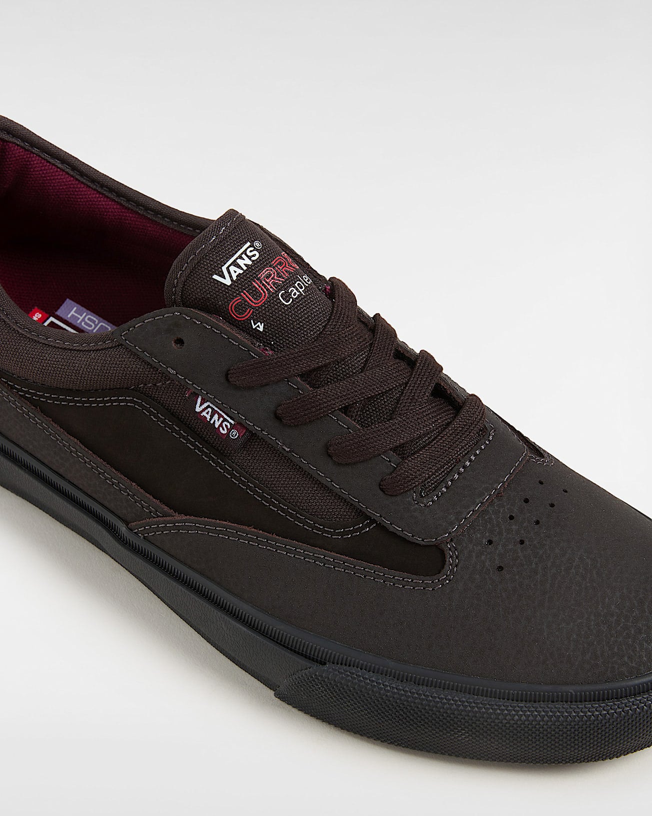 Close-up of brown Vans skate shoe featuring textured upper, lace-up front and CURRAN branding on tongue.