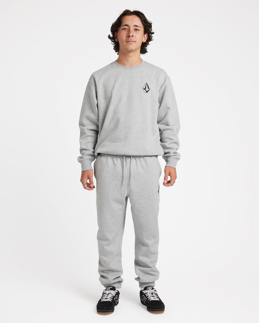 Model wearing a matching light grey Volcom sweatsuit with a black logo on the chest, drawstring pants, and black sneakers.