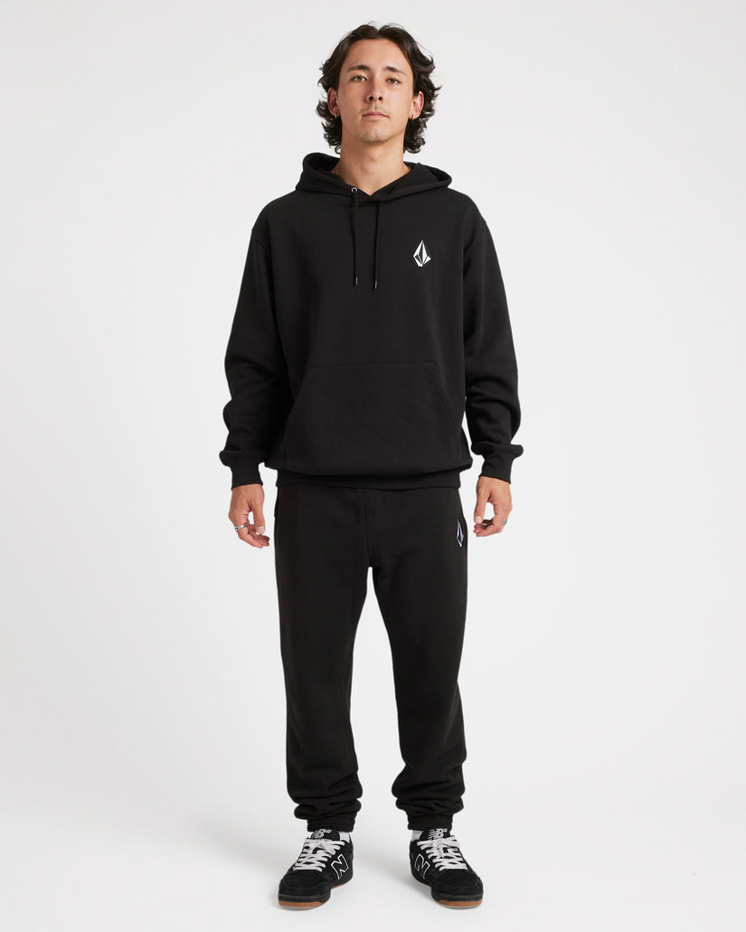 Full-body view of a model wearing a black Volcom hoodie and matching sweatpants with logo details, paired with sneakers.