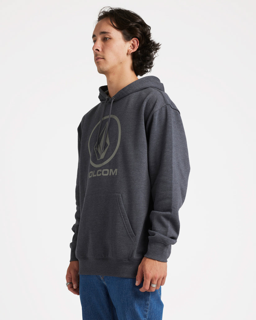 Side view of a male model wearing a dark grey Volcom hoodie with a large front logo, paired with blue jeans, against a plain backdrop.