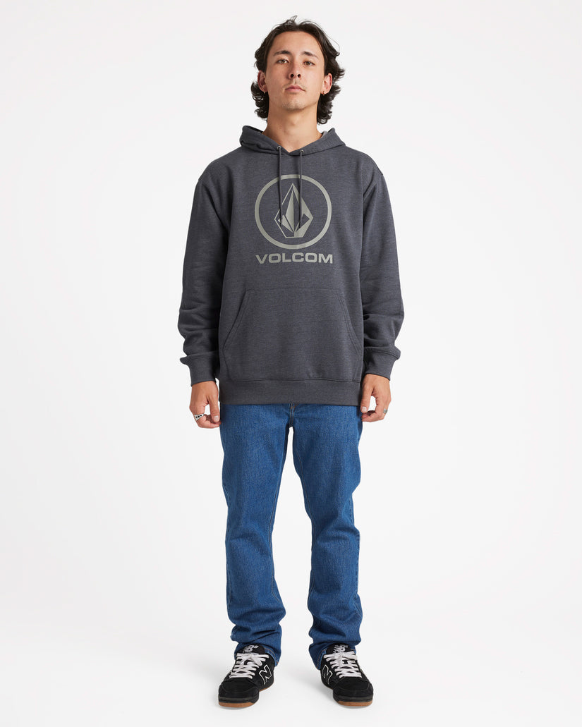 Full-body shot of a male model wearing a dark grey Volcom hoodie with a front logo, blue jeans, and black sneakers.