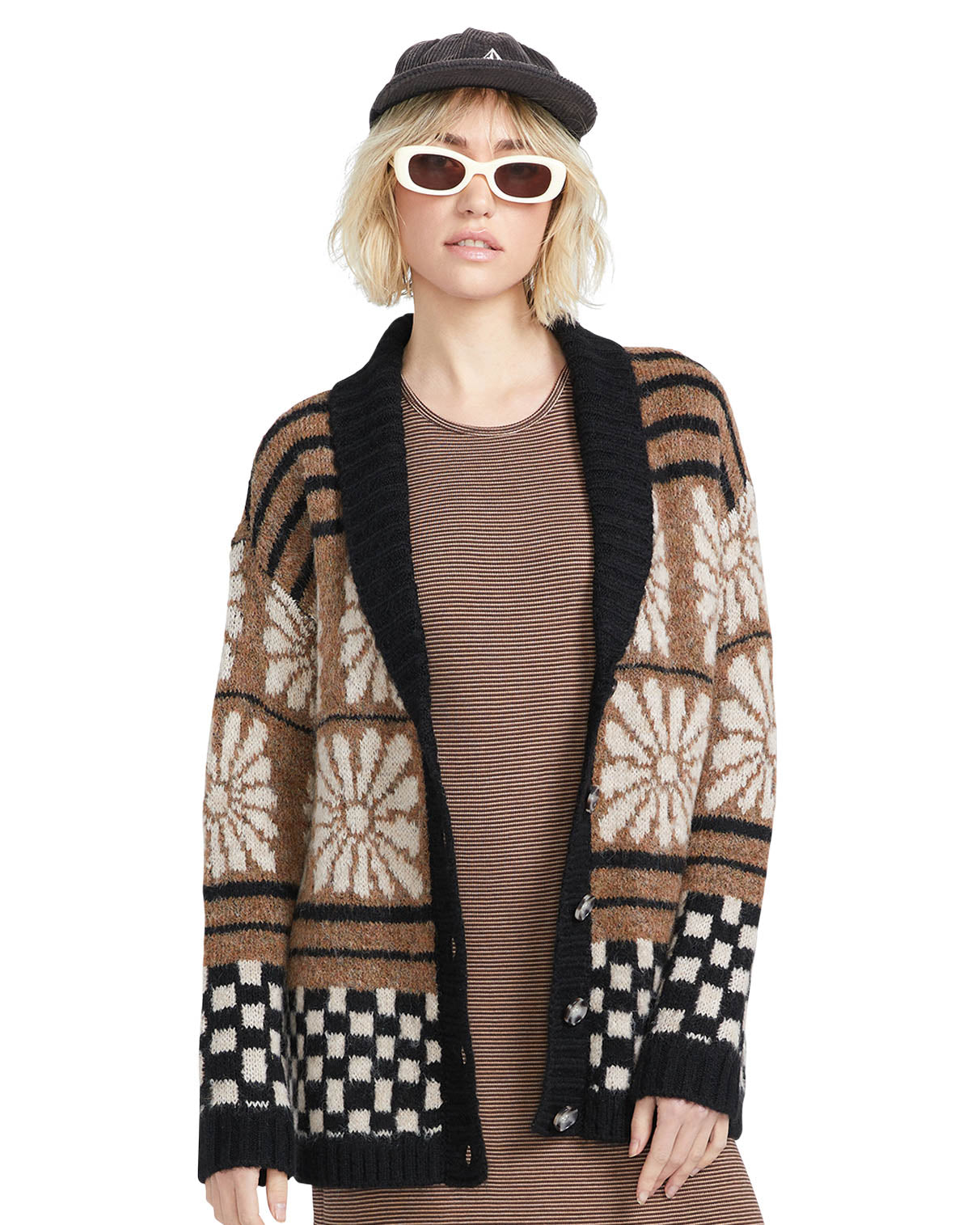 Model wearing a vintage-inspired knit cardigan with geometric and floral patterns, paired with a striped dress and sunglasses.
