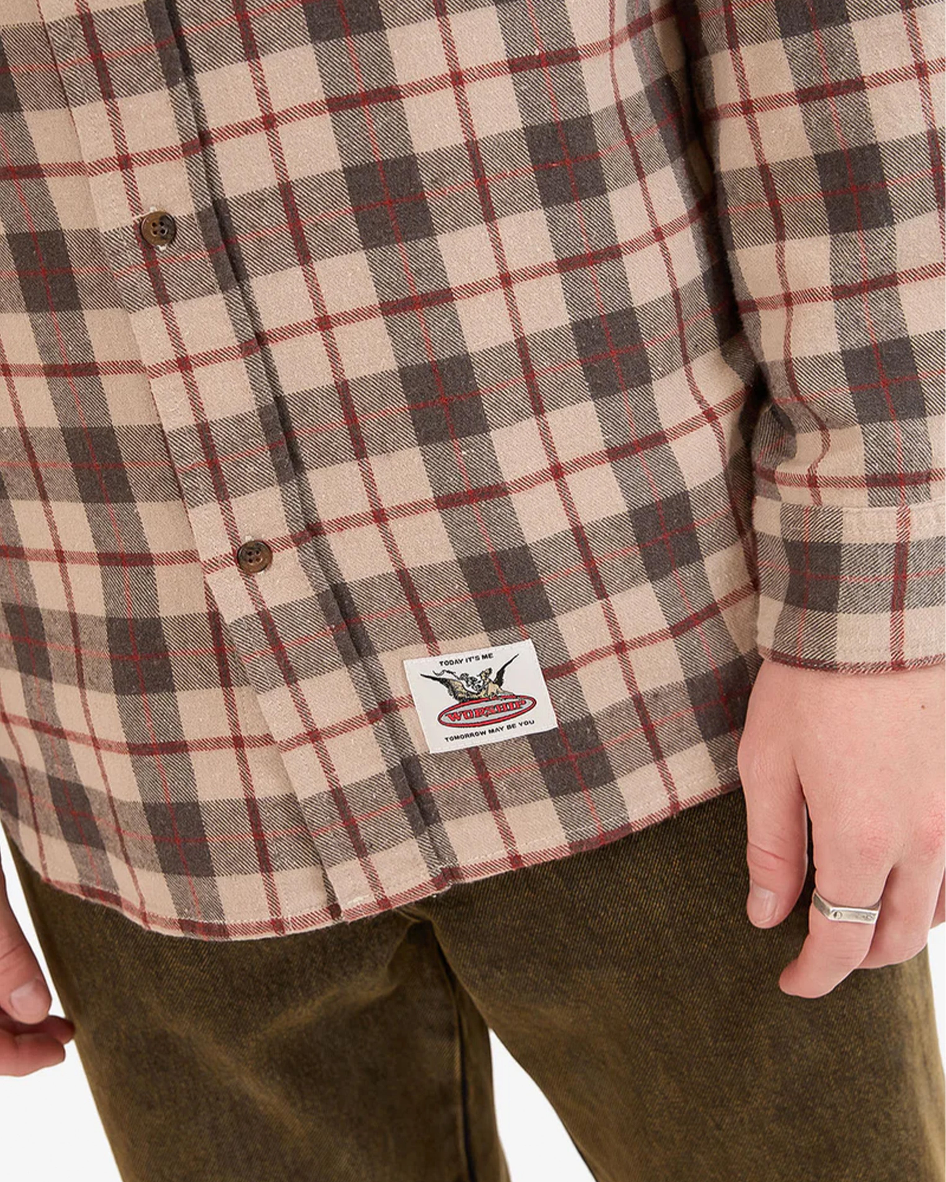 Close-up of woven logo patch on hem of flannel shirt