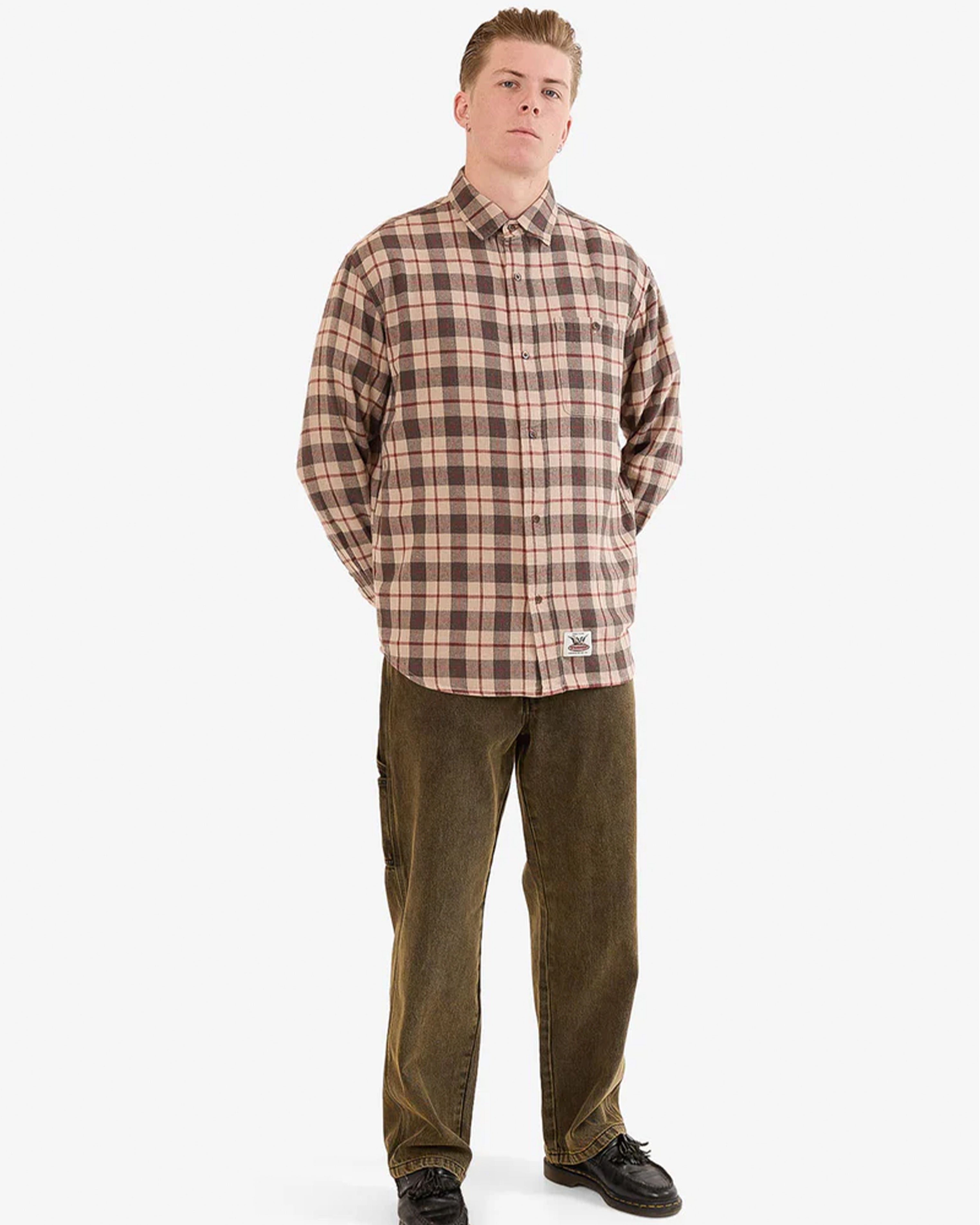 Full body view of brown plaid shirt styled with brown pants