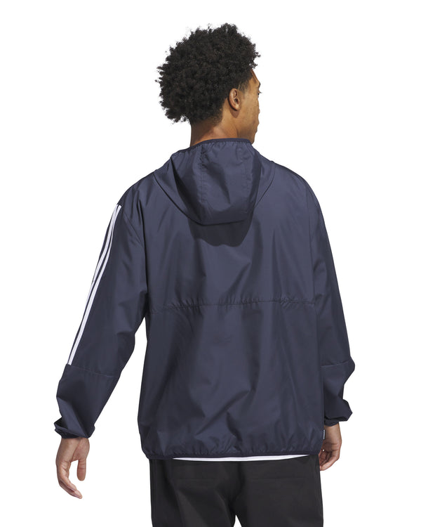 Back view of a man wearing a navy Adidas windbreaker jacket with a hood and white three-stripe detailing on the sleeves.