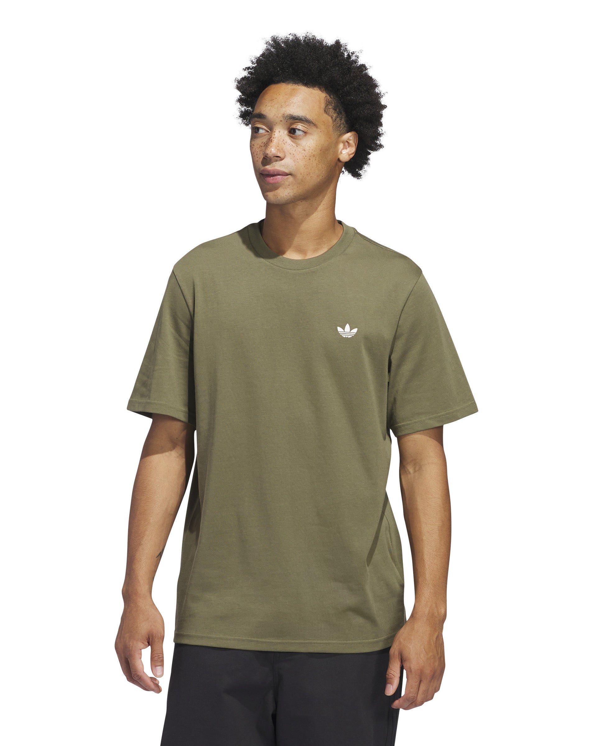 Model wearing an olive green Adidas t-shirt with a small white trefoil logo on the chest, paired with black pants.