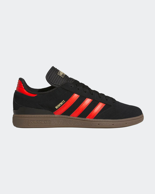 Black Adidas sneakers featuring vibrant red stripes, gold branding, a gum sole, and a sleek, low-profile design.