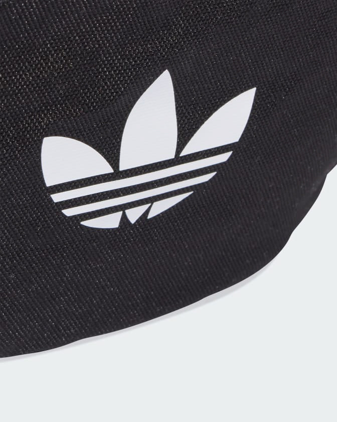Close-up of white adidas trefoil logo printed on black fabric.