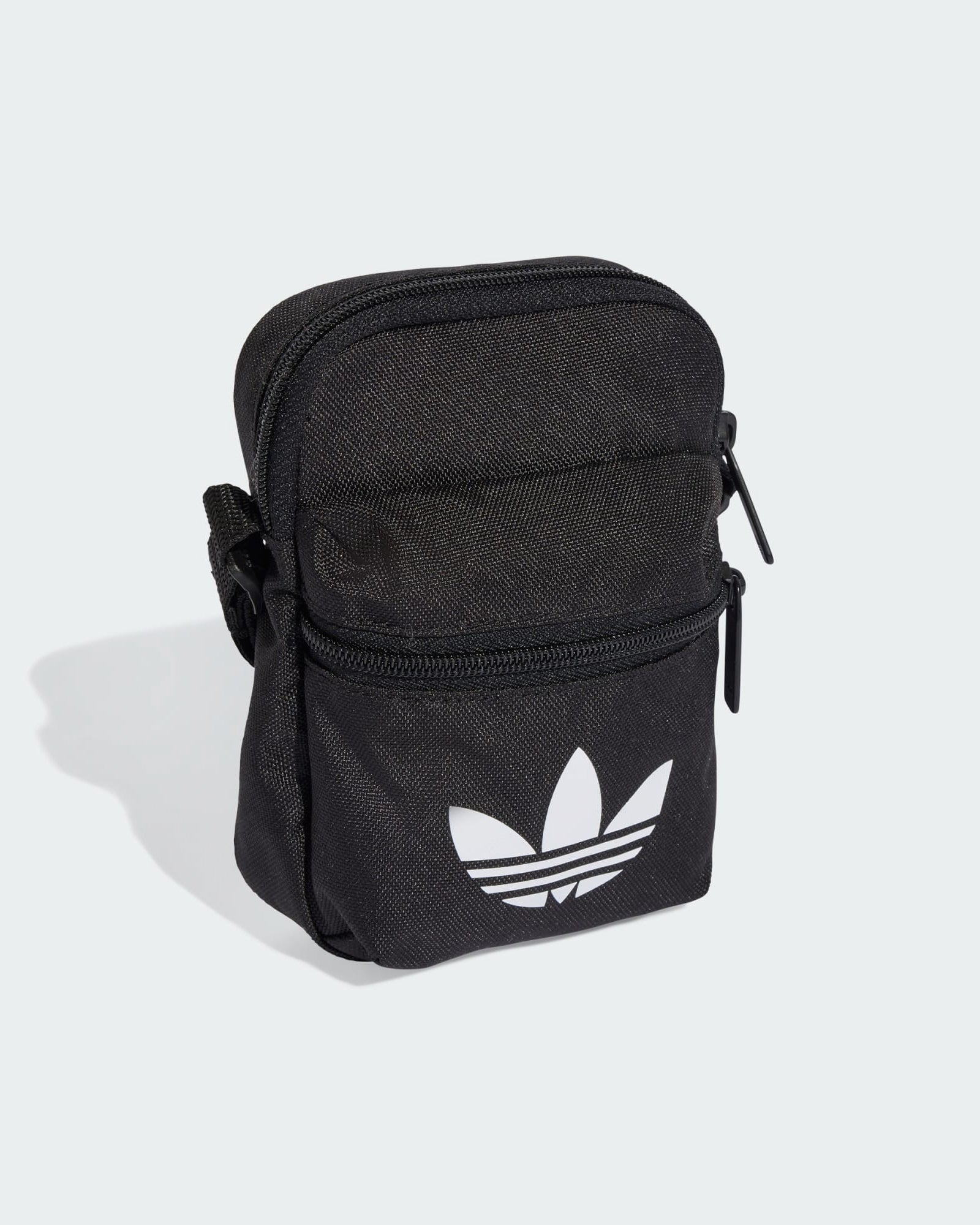 Angled view of adidas black mini bag with compact shape and durable fabric construction.