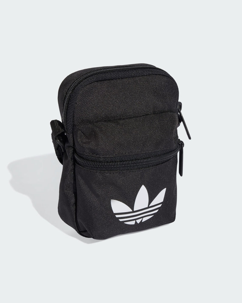 Angled view of adidas black mini bag with compact shape and durable fabric construction.