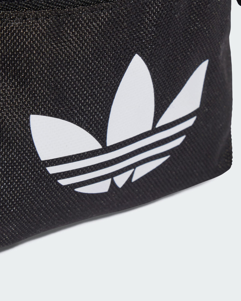 Close-up of white Trefoil logo on textured black fabric of adidas mini shoulder bag.