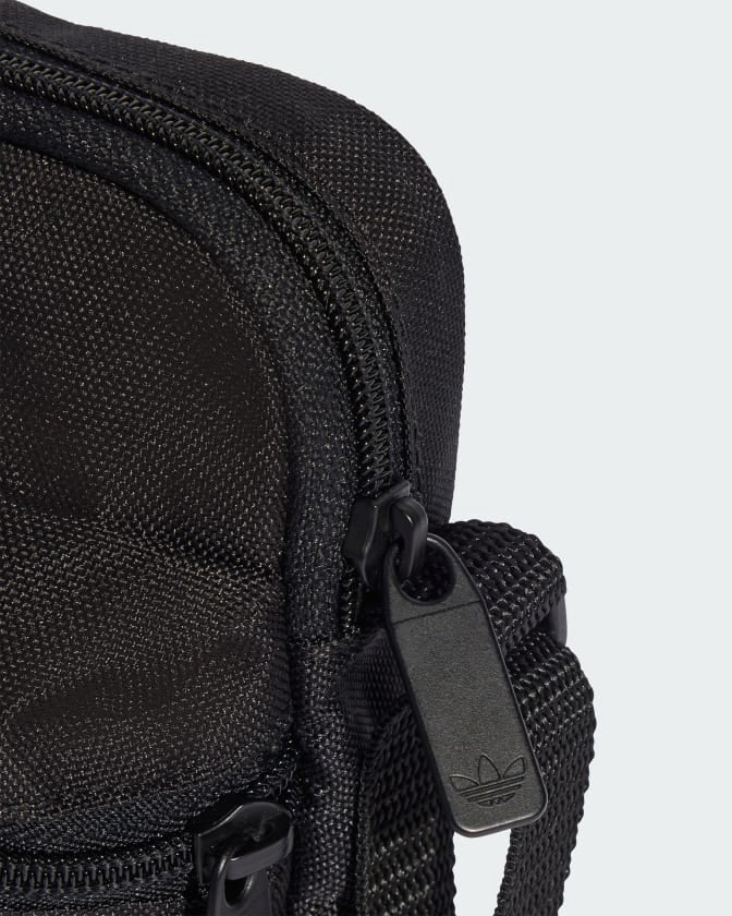Detail view of adidas bag zipper with logo-embossed puller and sturdy strap attachment.