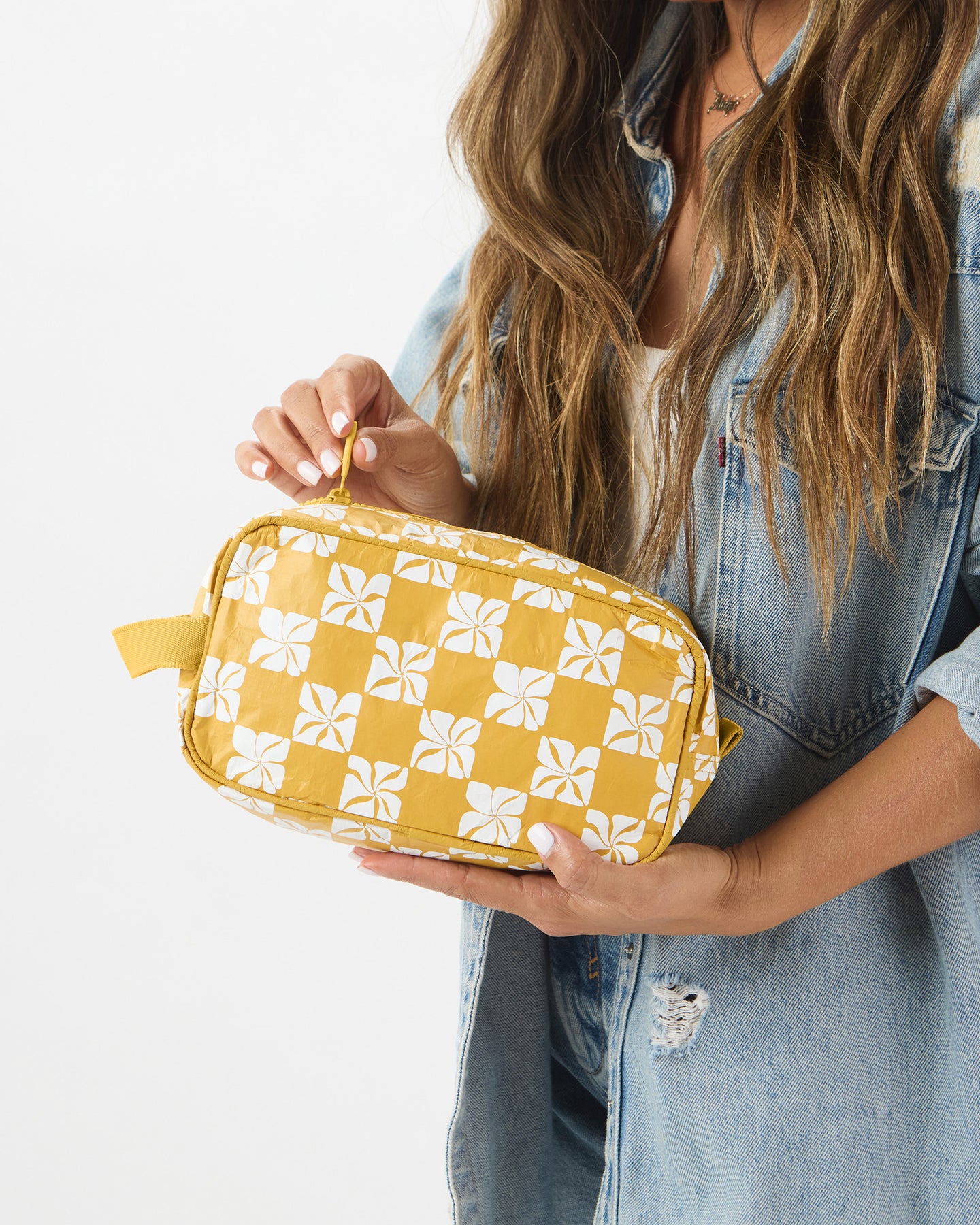 Woman holding yellow floral travel pouch with zip opening