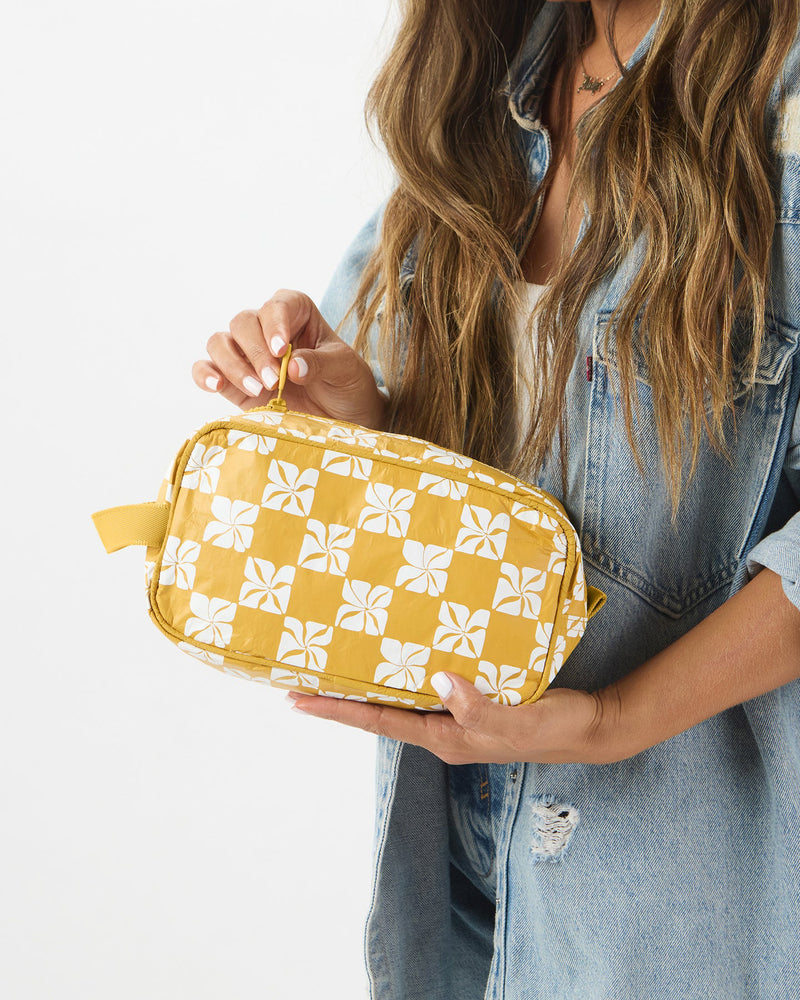 Woman holding yellow floral travel pouch with zip opening