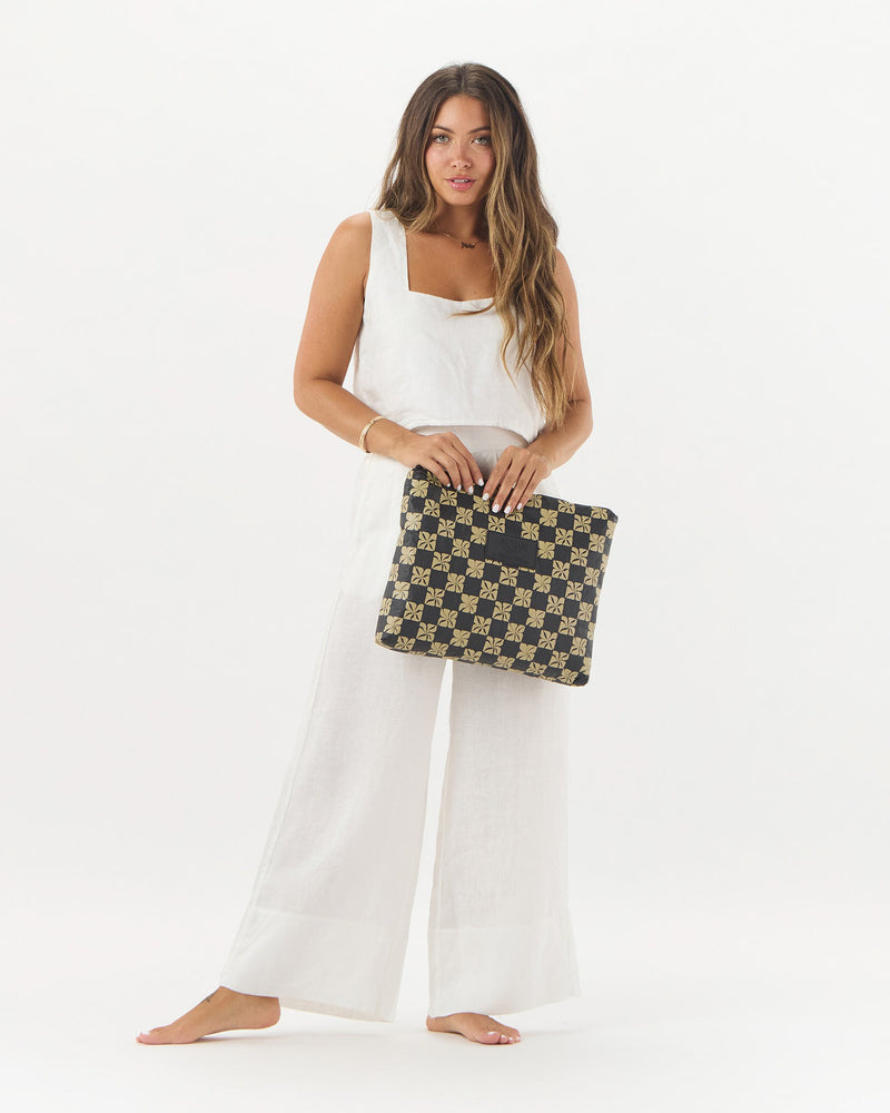 Model holding ALOHA pouch in floral checkerboard print, styled with an all-white outfit for contrast
