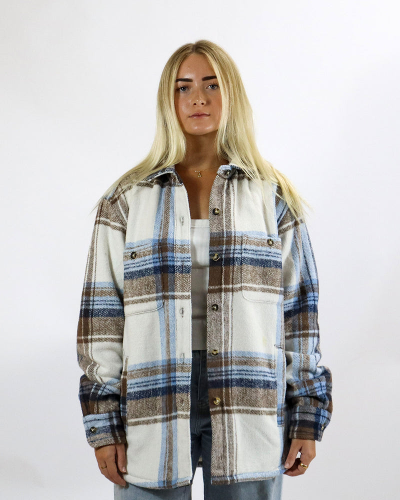 Women's oversized check shacket in cream, brown and blue tones with chest pockets, front view