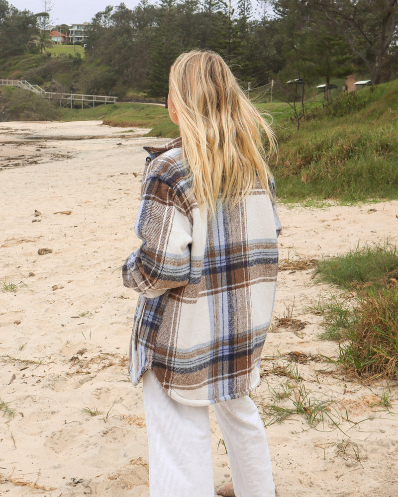 Back view of cream and blue check shacket styled casually on the beach