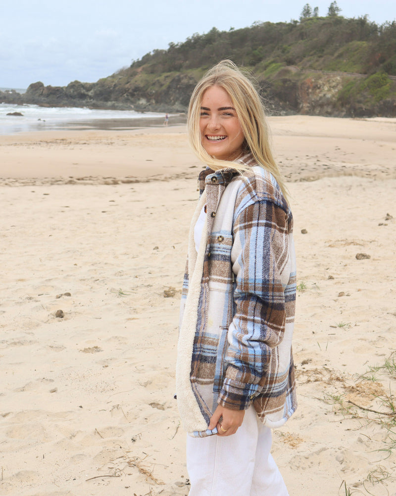 Side view of oversized cream and brown check shacket with button detail, worn open
