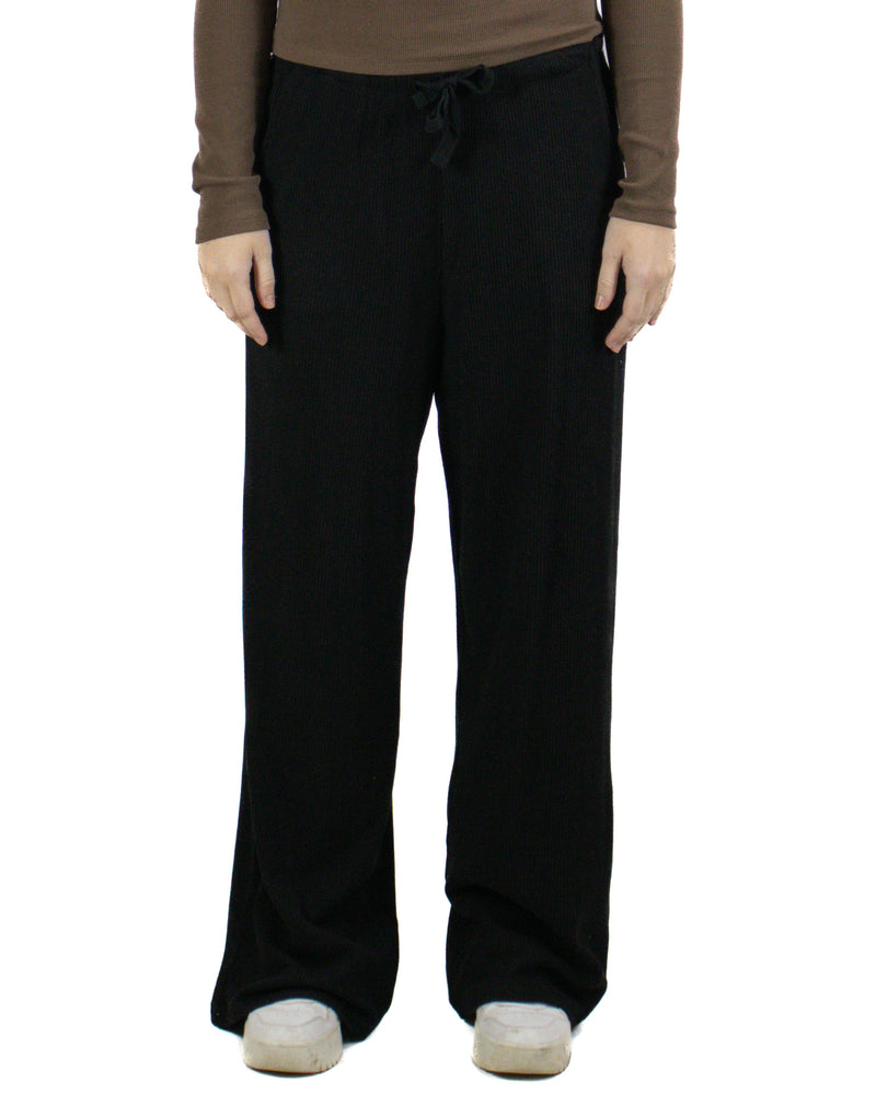 Woman wearing black ribbed wide-leg pants with drawstring waist and white sneakers