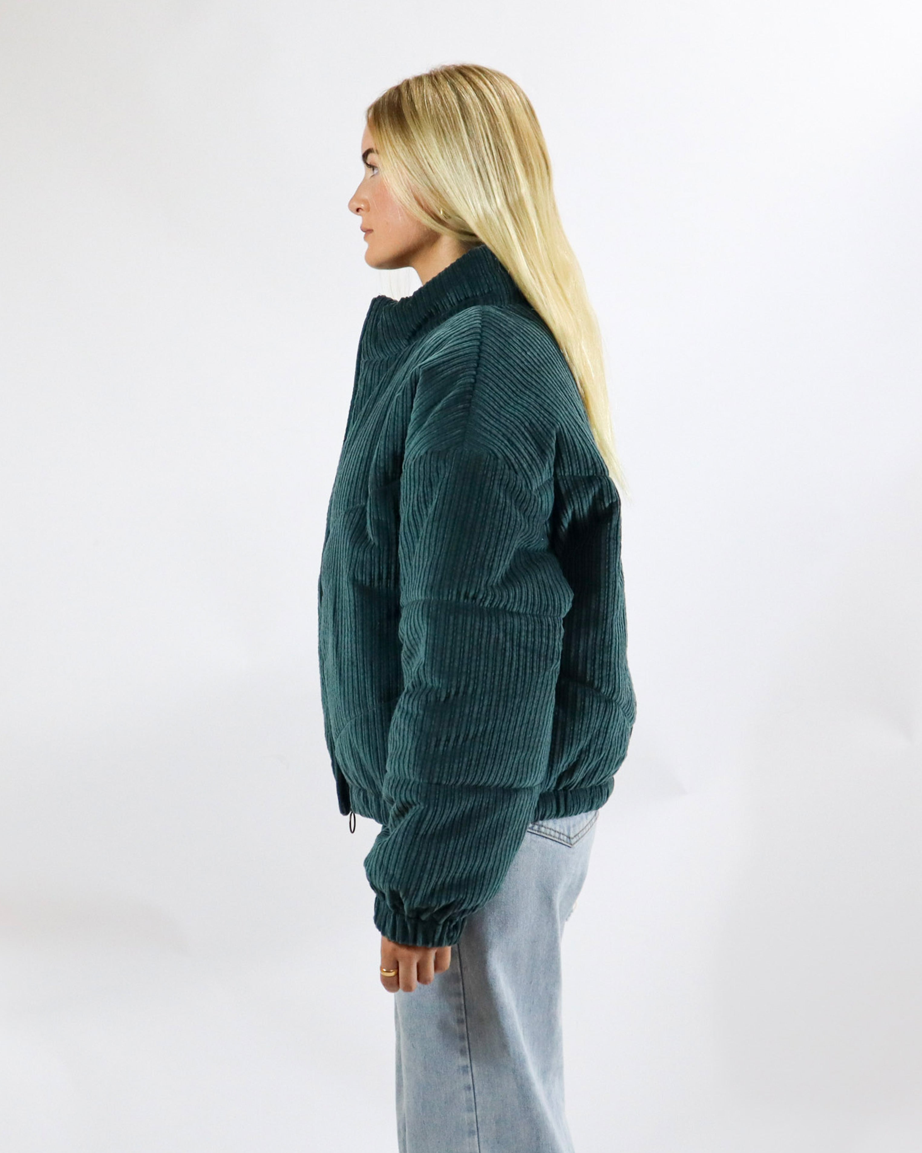 Side profile of oversized dark green corduroy jacket with long sleeves