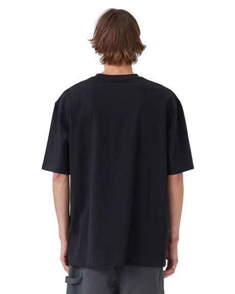 Back angle of oversized black tee worn with dark grey cargo shorts.